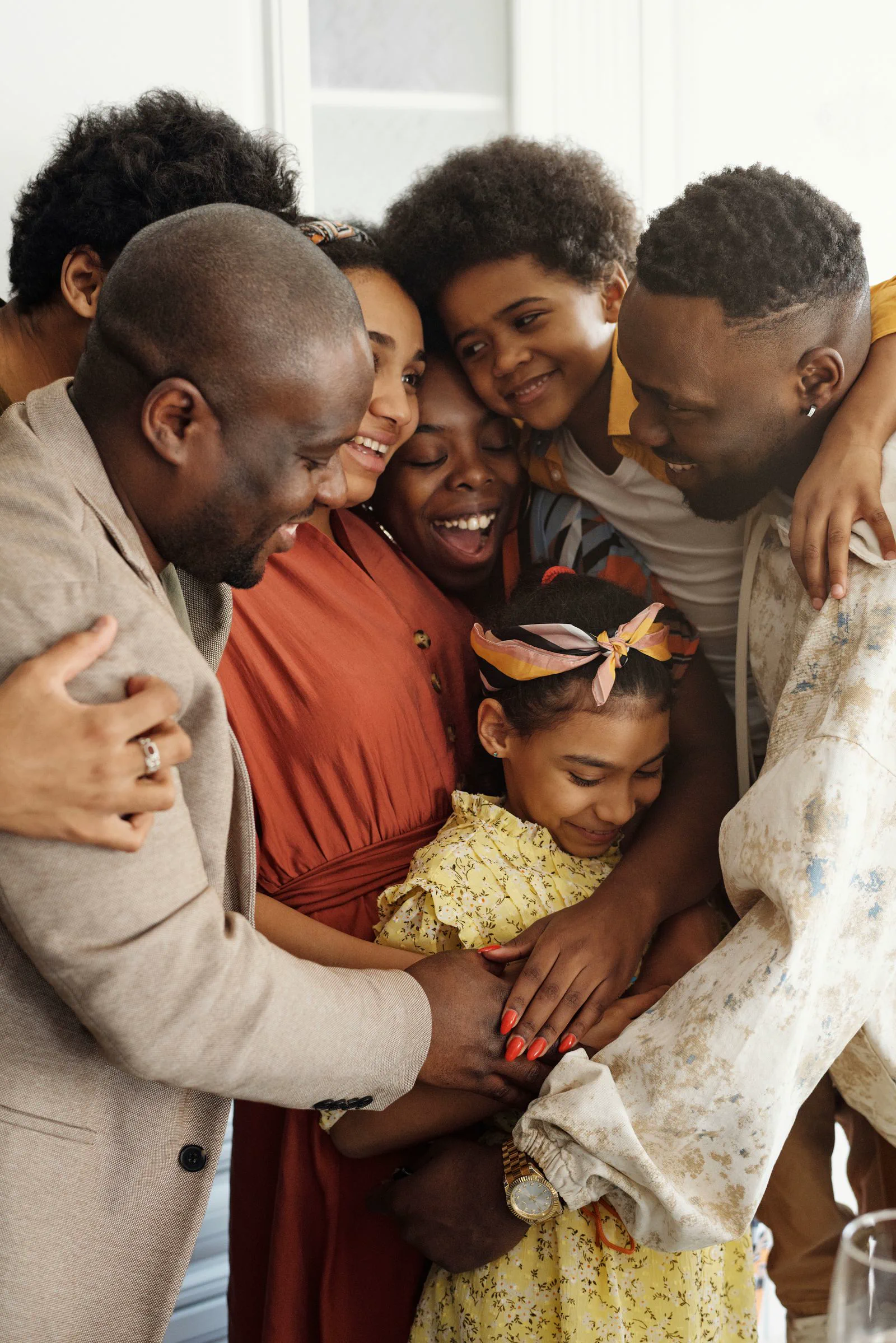 A family gathered close together, smiling, in a bright room.