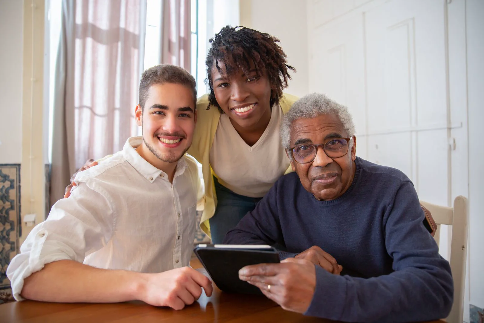 A family and caregiver looking at a tablet together at home.